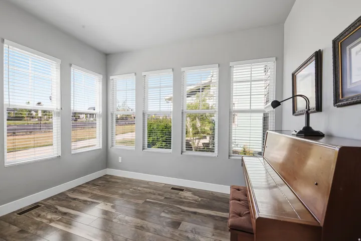 Multiple windows, wood-finish flooring, light gray wall paint, white window blinds, white trim