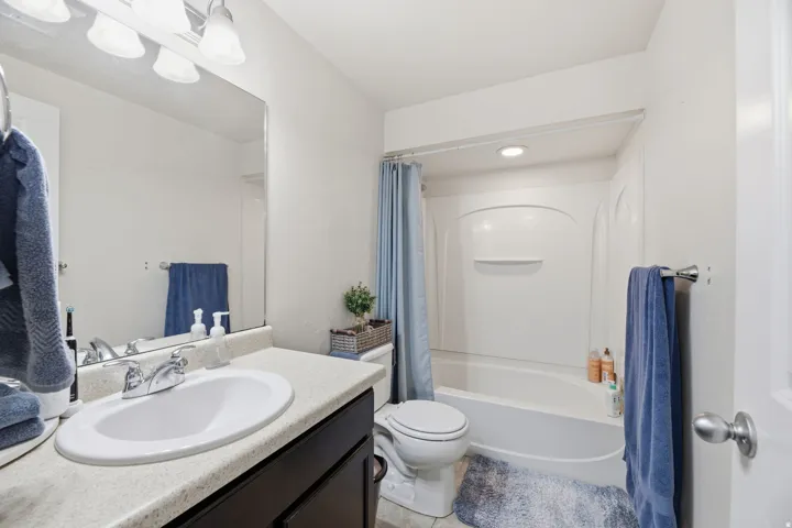 White vanity with integrated sink, chrome faucet, and expansive wall mirror
