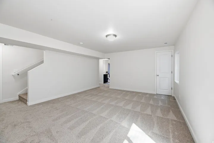 Spacious room with light neutral carpeting, white walls, and a contemporary ceiling fixture