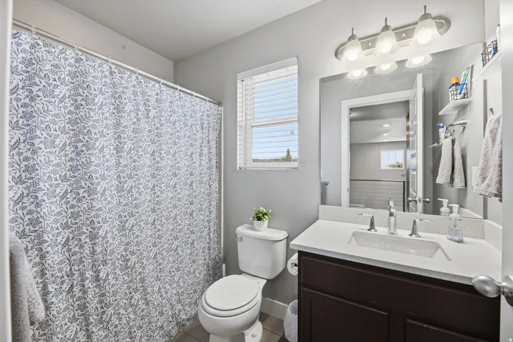 Bathroom featuring a dark wood-finish vanity with an undermount sink, a light-toned countertop, and a window with blinds