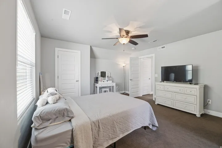 Neutral wall paint, ceiling fan with integrated lighting, white paneled doors, and brown carpeting
