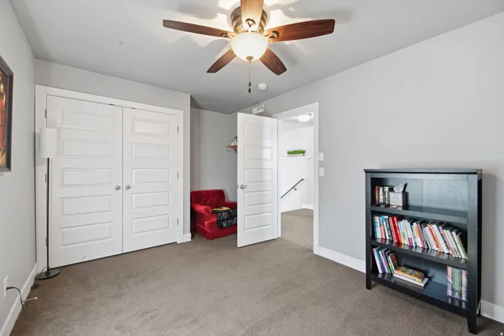 Wall-to-wall carpeting and a ceiling fan with integrated lighting