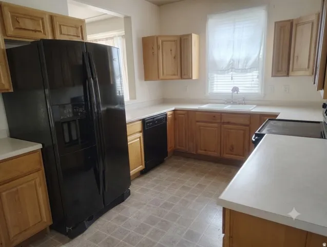 Kitchen featuring wood cabinetry, light-toned countertops, a double basin sink, and tile-look flooring