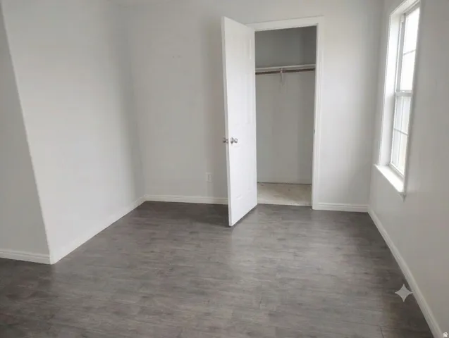Wood-finish flooring, white walls, white trim, recessed window, and a built-in closet with a white door