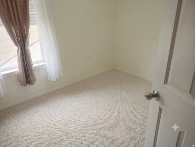 Light-colored carpeted flooring with baseboards and a paneled interior door