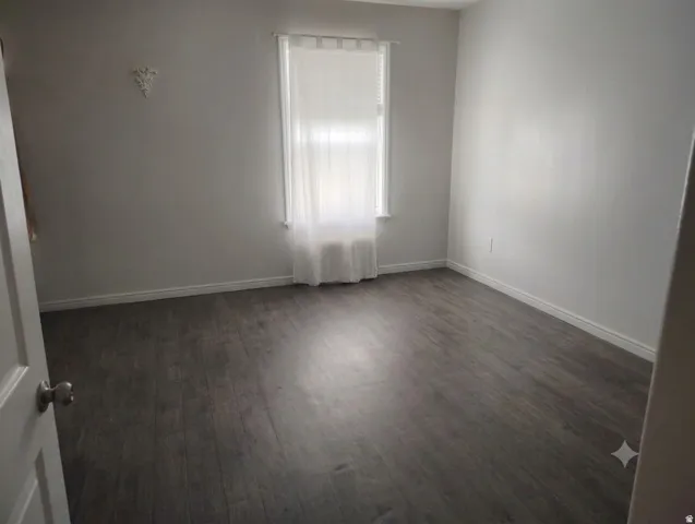 Spacious room featuring wood-finish flooring and a window with natural light