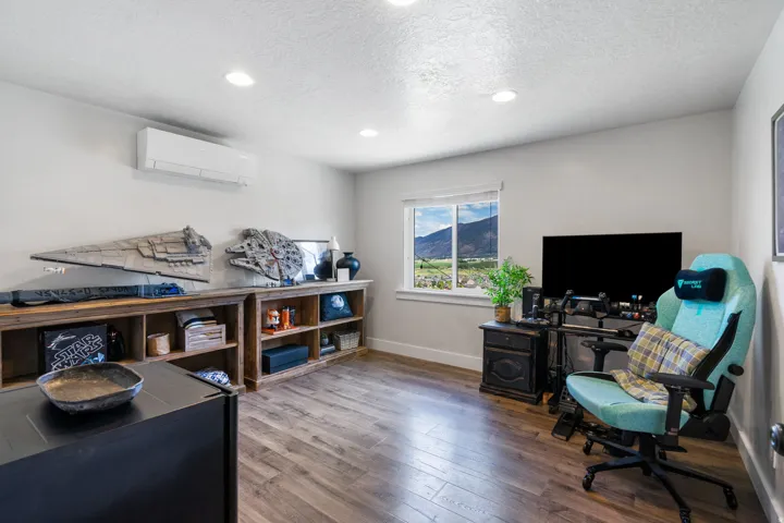 Recessed lighting with wood-finish flooring, split air conditioning unit, and a window providing natural light