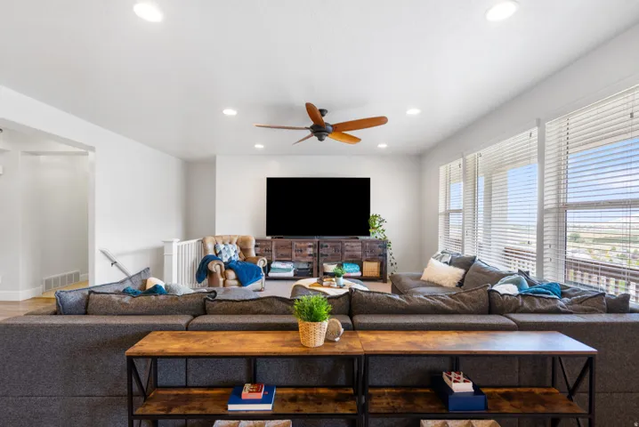 Argon gas filled windows, Open-concept living space featuring a ceiling fan, recessed lighting, and large windows with blinds