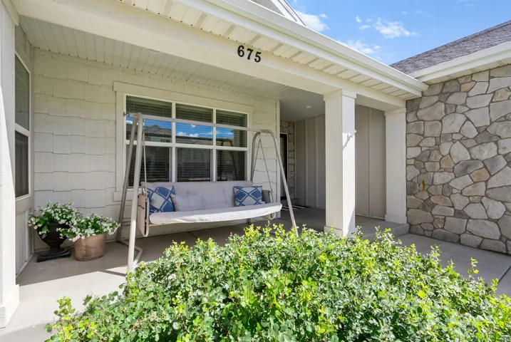 Covered front porch featuring stone, textured shake siding, white columns, and multi-pane windows