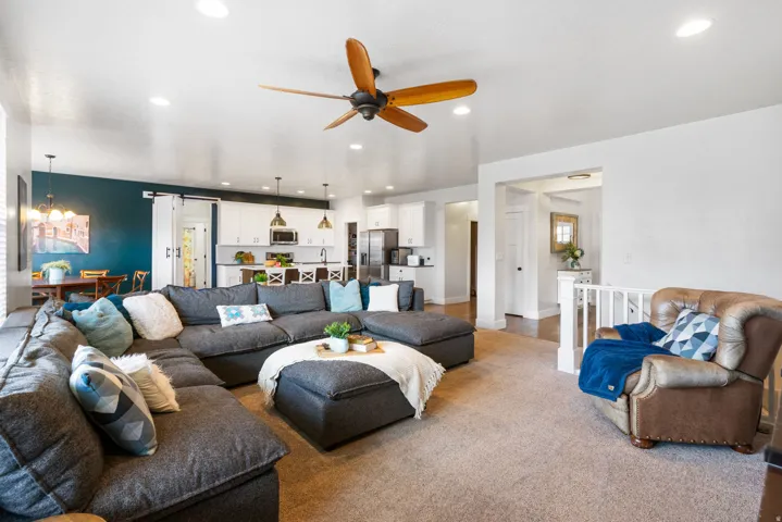 Open-concept living space featuring a sectional arrangement, wood-finish flooring / carpet, recessed ceiling lighting, and a ceiling fan