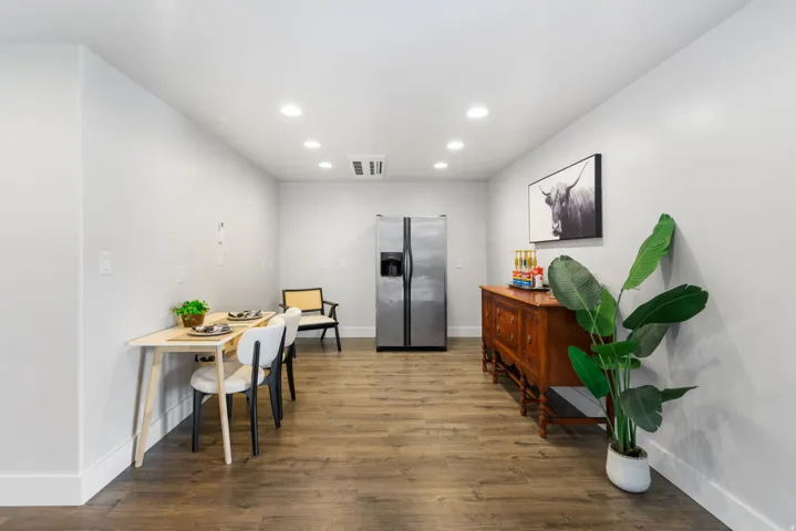 Potential kitchen area.Recessed lighting, wood-finish flooring, white baseboards, and stainless steel refrigerator
