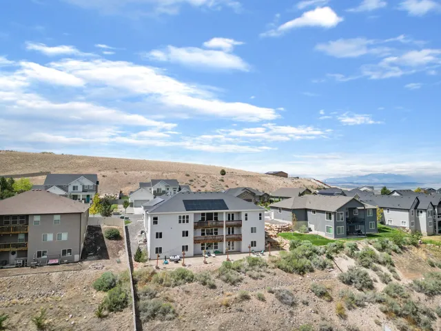 Rear exterior featuring multiple balconies, ground-level patio, and solar panels