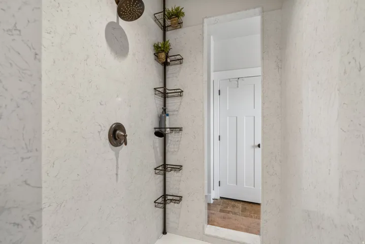 Shower with stone-finish walls, a bronze showerhead, and matching bronze controls