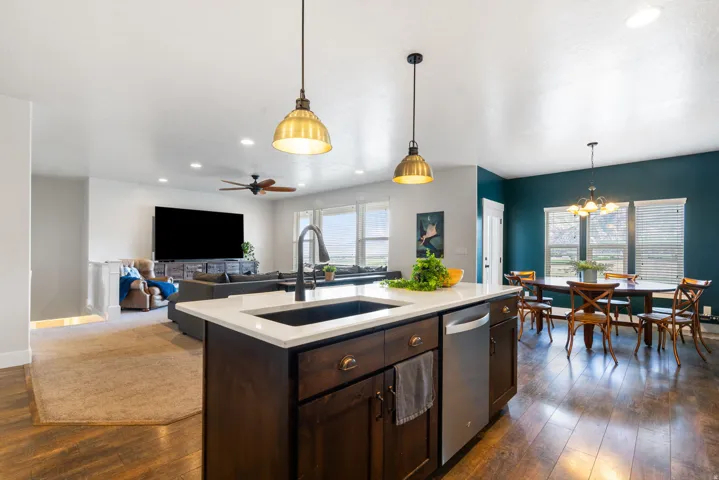 Argon gas filled windows, Kitchen island with a white countertop and dark wood-finish cabinetry, stainless steel dishwasher, and a deep basin sink with a black gooseneck faucet