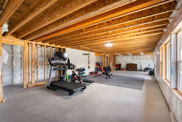 Unfinished lower level with exposed ceiling joists, concrete flooring, recessed lighting, and multiple windows