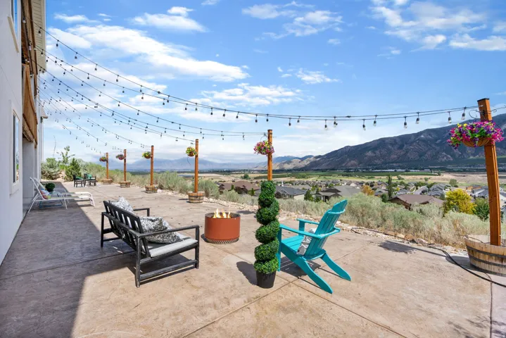 Expansive concrete patio with string lighting and a built-in fire pit