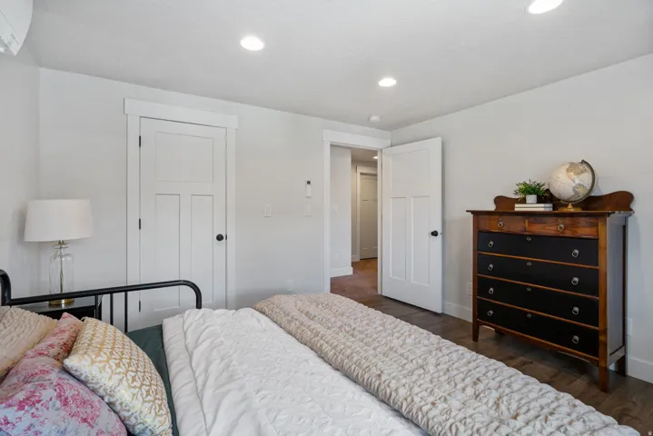 Recessed lighting illuminates wood-finish flooring and a white painted door with black hardware