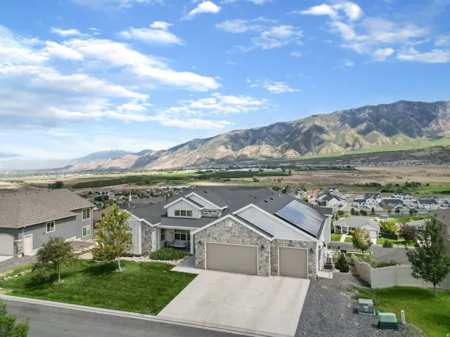 Stone and siding exterior with a dark shingle roof, solar panels, and an attached 3-car garage