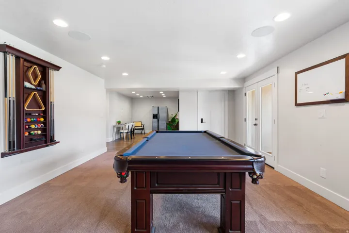 Recessed lighting, carpet flooring, white walls, and a built-in cue rack