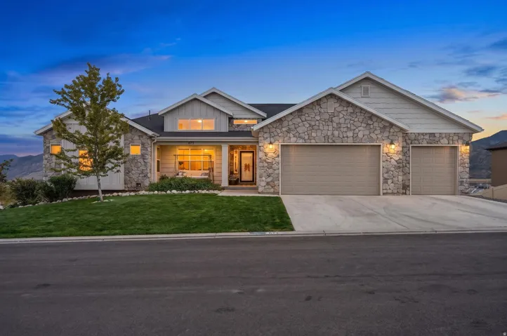 Stone and stucco exterior with a covered porch 3 car garage