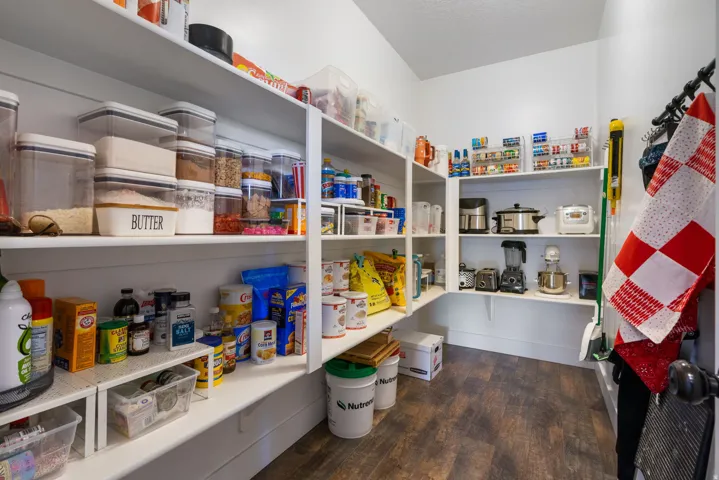 Expansive pantry featuring extensive built-in shelving, wood-finish flooring, and white painted walls