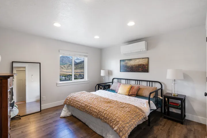 Recessed ceiling lighting, wood-finish flooring, mountain scenery, mini-split HVAC unit, and a window with blinds