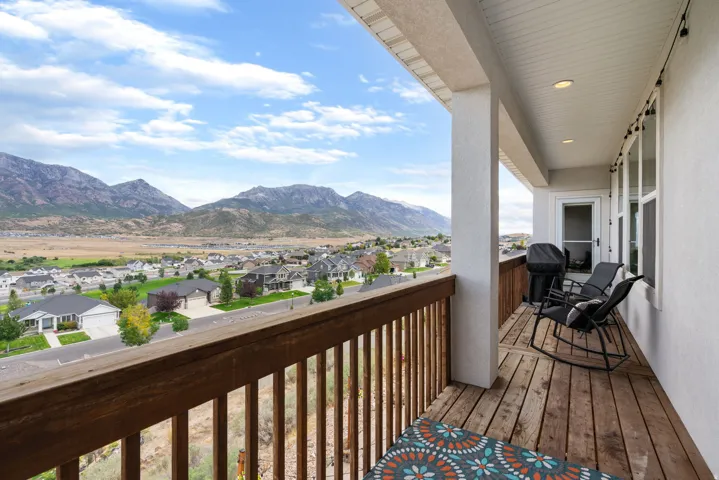 Expansive wood-deck balcony with mountain scenery, recessed lighting, and a white exterior door
