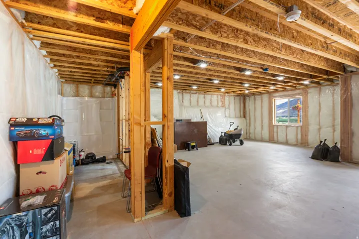 Unfinished basement featuring exposed wood joists, recessed lighting, a concrete floor, and a window providing natural illumination
