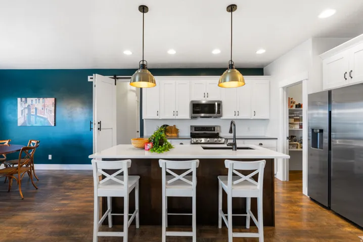 Kitchen featuring a central island with countertop seating, white cabinetry, dark wood-finish flooring, and recessed lighting