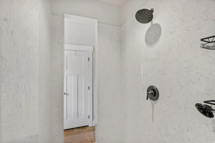 Textured shower enclosure with a dark bronze showerhead and matching control