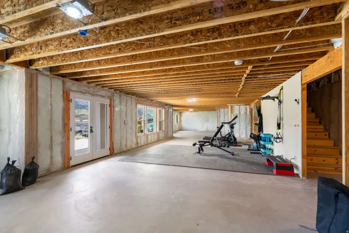 Unfinished basement featuring exposed wood joists, concrete flooring, and multiple windows