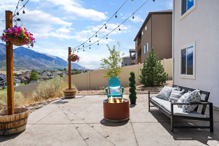 Expansive concrete patio with string lights, a fire pit, and mountain scenery