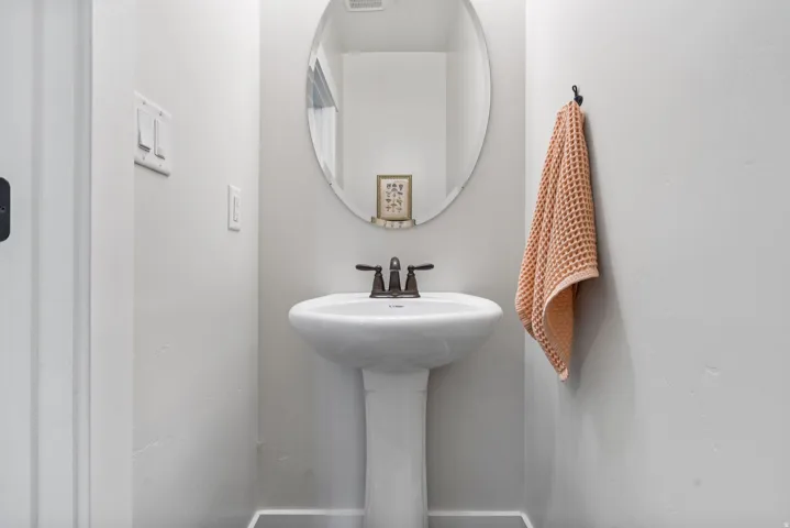 Half bath . Pedestal sink with dark bronze faucet, oval mirror