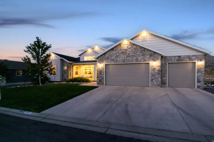Stone facade with shake siding accents, multiple garage bays, covered front porch, and a concrete driveway