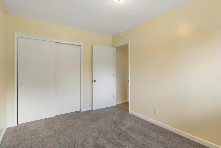 Neutral wall color, grey carpet, white trim, sliding closet doors, and recessed lighting
