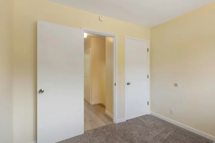 Wall-to-wall carpeting with light-toned walls and white trim