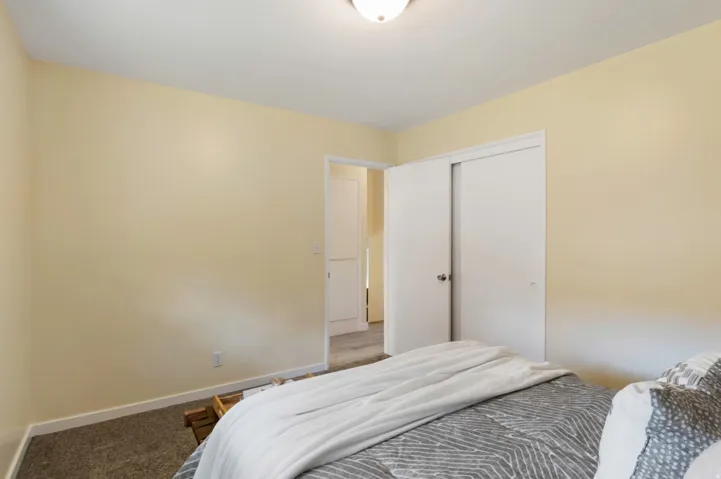 Carpeted flooring, light-toned wall paint, overhead flush-mount lighting, and white sliding closet doors