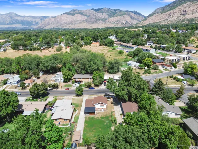 Mountainous backdrop, established residential area, mature trees, paved roads, and clear skies