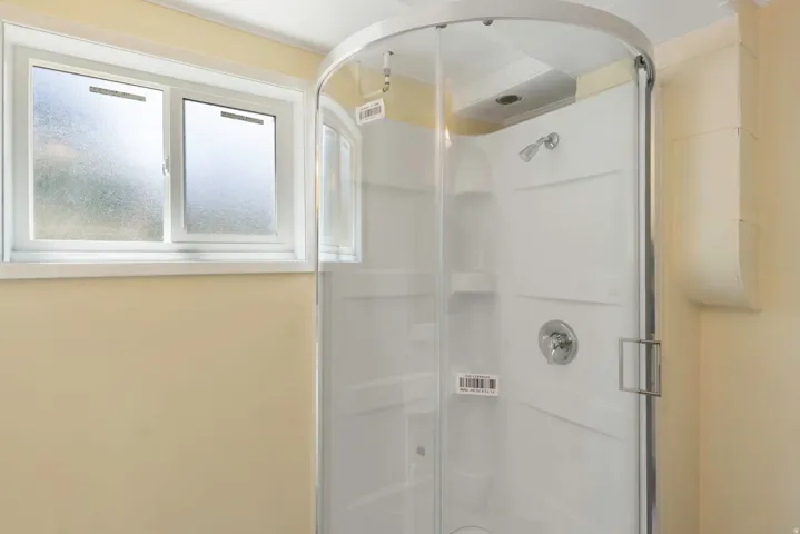 Enclosed shower with clear glass door, chrome fixtures, and built-in shelving