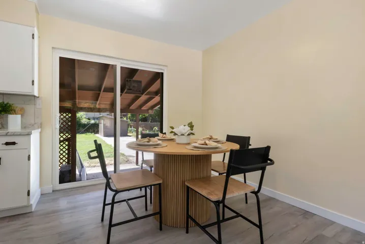 Sliding glass door, light-toned walls, wood-finish flooring, white cabinetry, stone-look countertop