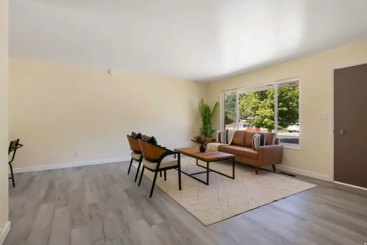 Spacious living area featuring light wood-finish flooring, a large picture window, and neutral wall tones