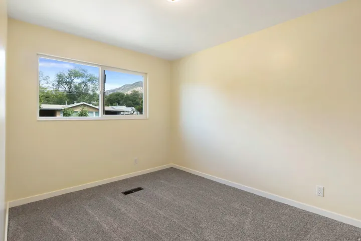 Carpeted flooring, light-toned wall paint, white trim, and a window with white framing
