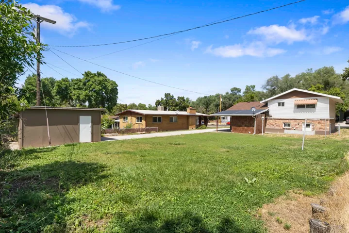 Expansive grassy yard with a detached utility shed and mature trees
