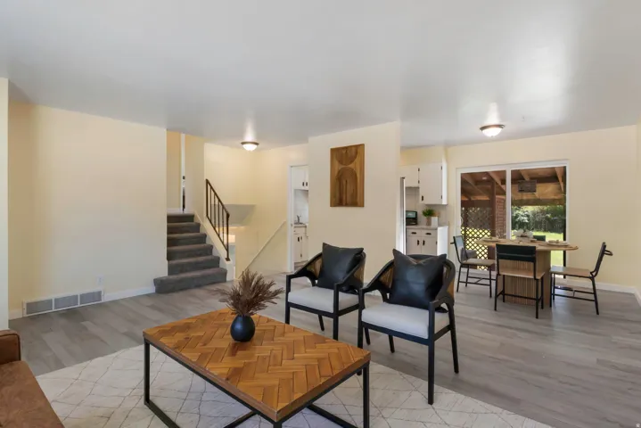 Light-toned wood-finish flooring, staircase with carpeted treads and metal railing, recessed ceiling lighting, and sliding glass doors to an outdoor area