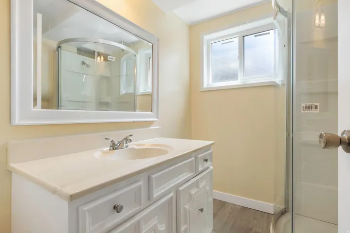 White framed mirror over a single vanity with a built-in sink and a light-colored countertop