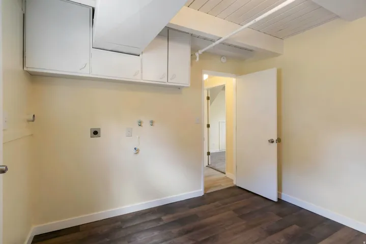 Dark wood-finish flooring, built-in overhead cabinetry, exposed beam ceiling, and a light wall color