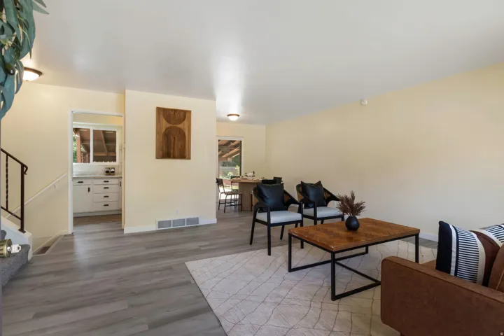 Open-concept living space featuring wood-finish flooring, recessed lighting, and a white staircase with a black metal handrail
