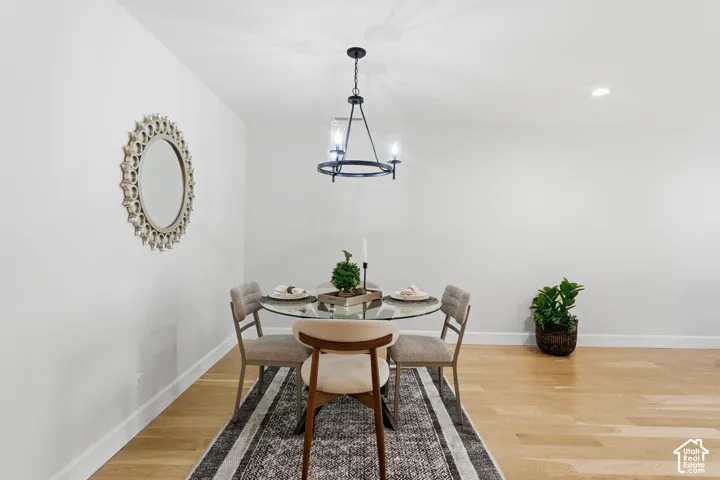 Light wood-finish flooring, recessed lighting, and a modern chandelier with a matte black finish