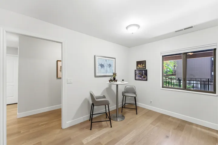 Recessed ceiling lighting, wood-finish flooring, white wall paint, and a rectangular window with dark trim