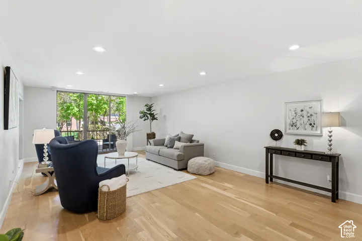 Hardwood flooring throughout, recessed lighting, and a full-height glass panel balcony door